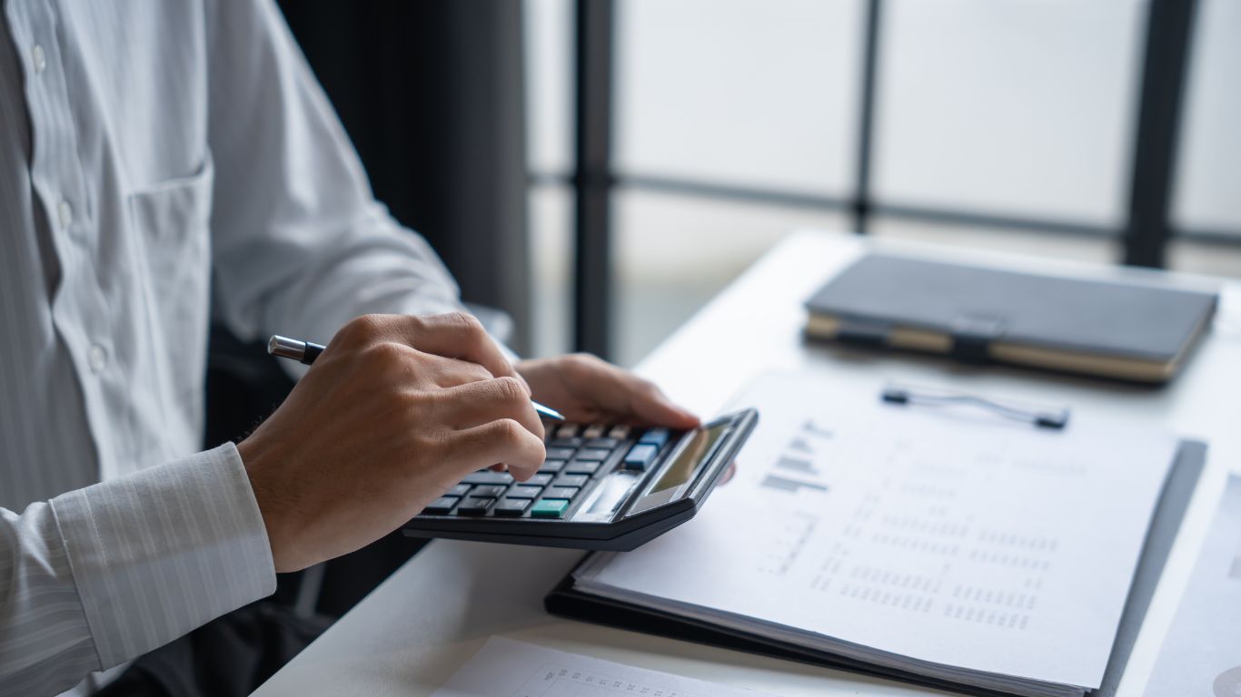 Person calculating costs with documents and calculator, reviewing mold remediation financing options.
