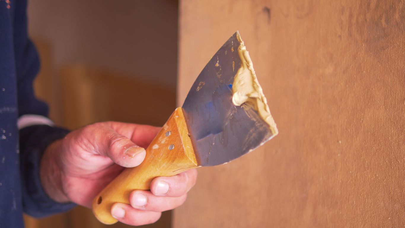 Worker applying filler during drywall and interior painting.