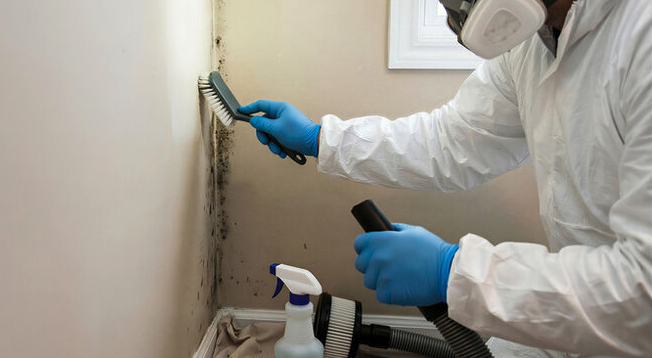 Commercial Mold Remediation 2 A professional in safety gear seals off a contaminated area during cleanup, representing the importance of accessible mold remediation financing for safe home recovery.